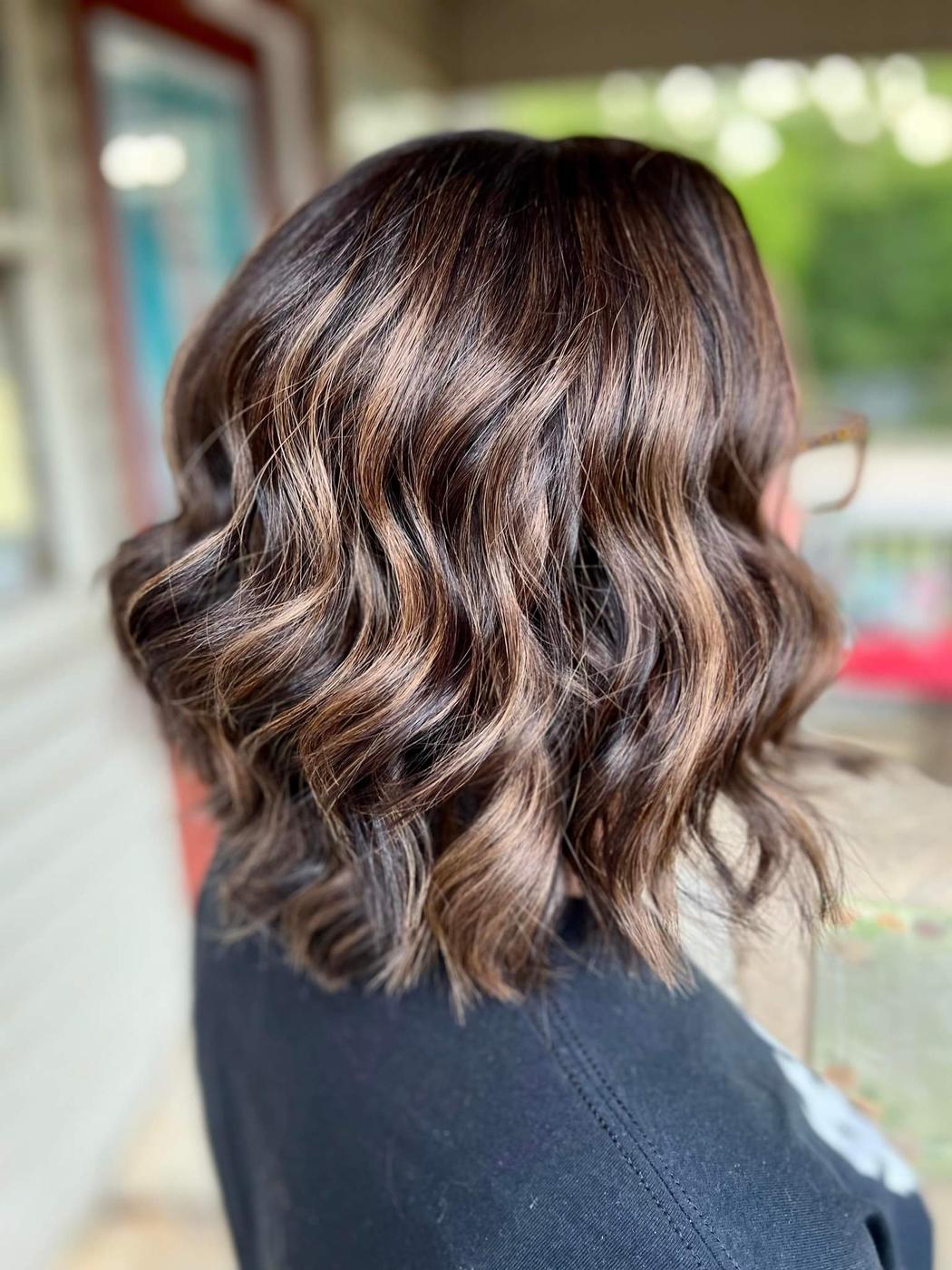 A shoulder length brunette cut, waved, lighter through the mid lengths.