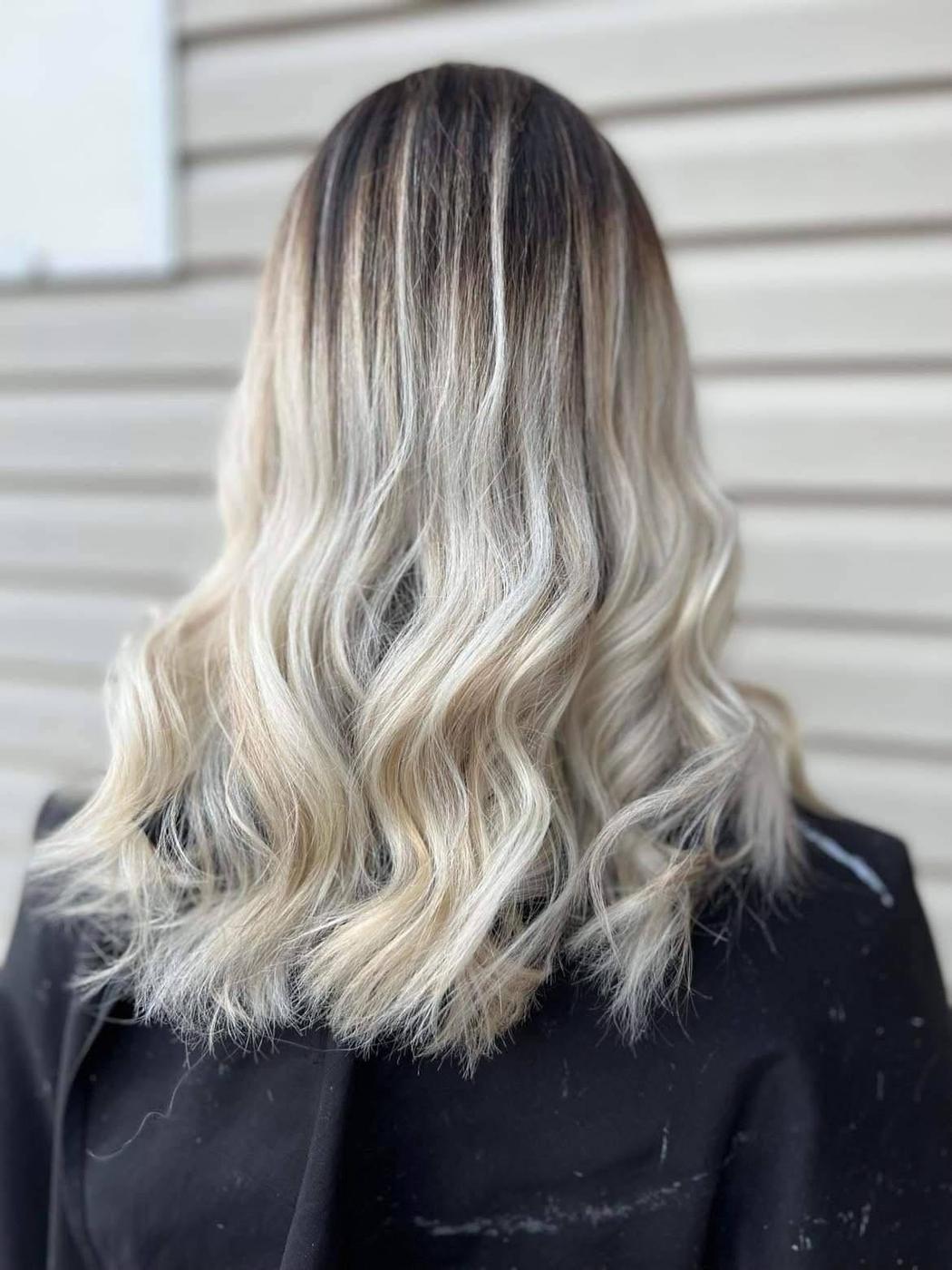 Cool toned blonde with a deliberately dark root, waved.